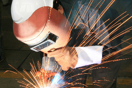 戴電焊手套手持焊接面罩正在專心焊接工人