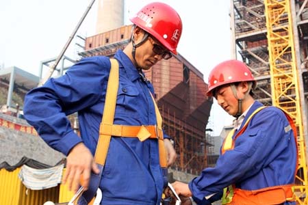 进入高空作业前，同事正在帮他穿戴高空安全带